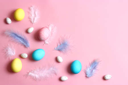 Easter composition of painted eggs and feathers on a colored background.