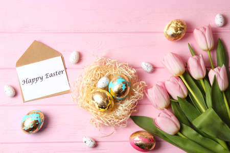 Easter composition of painted eggs and feathers on a colored background.