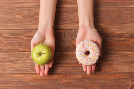 donut and apple in female hands. Healthy and unhealthy food. choice.の写真素材