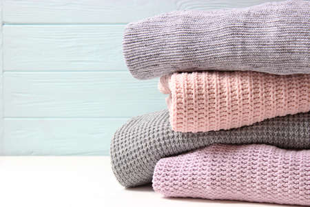Warm knitted sweaters folded in a stack on a light background close-up.の写真素材