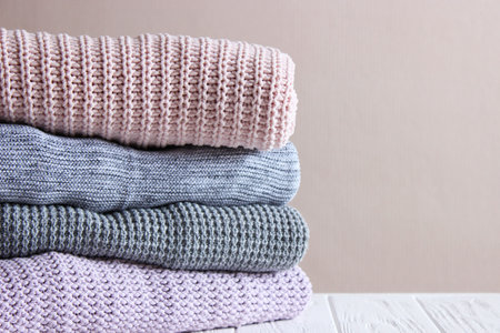 Warm knitted sweaters folded in a stack on a light background close-up.の写真素材