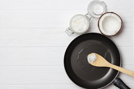 Coconut oil and a frying pan on a wooden table close-up.の写真素材