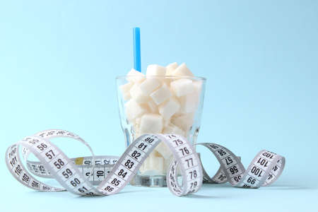 sugar in a glass and measuring tape on a colored background.