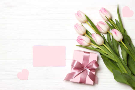 A bouquet of beautiful tulips and a gift on a wooden background top view.の写真素材