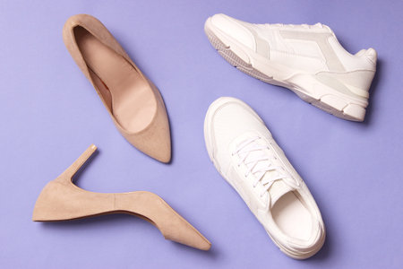white sneakers and high heel shoes on a colored background top view.の写真素材