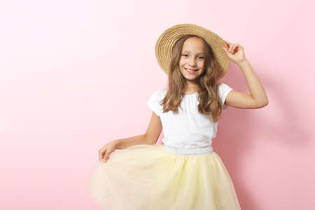 Little cheerful smiling girl in fashionable clothes on a colored background.
