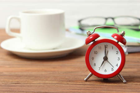 alarm clock on a colored background, a cup of coffee and stationery