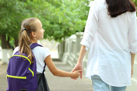 Cute schoolgirl with a school backpack in the schoolyard.の写真素材
