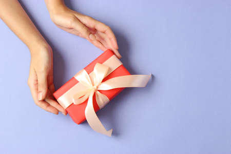 gift in female hands on a colored background top view.の写真素材