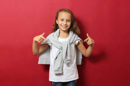 Little cheerful smiling girl in fashionable clothes on a colored background.の写真素材