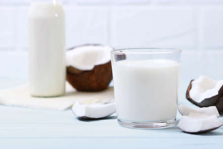 Milk and broken coconuts on the table. Vegetable milk, a veggie drink.の写真素材