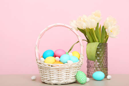 Easter eggs in a basket and flowers on the table.の写真素材