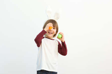 Little cute boy with Easter eggs in his hands and bunny ears on his head