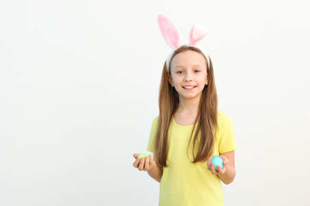 Portrait of a little cute smiling girl with bunny ears and easter eggs in handsの写真素材