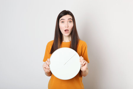 Girl holds a mechanical clock on a colored background