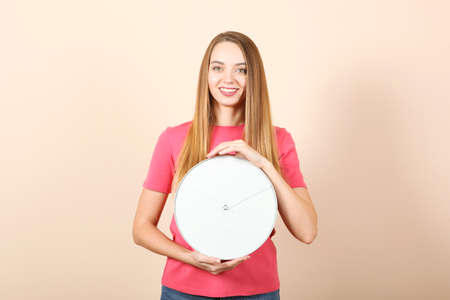 Girl holds a mechanical clock on a colored backgroundの写真素材