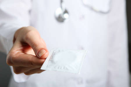condoms in the hands of a doctor in a white coatの写真素材