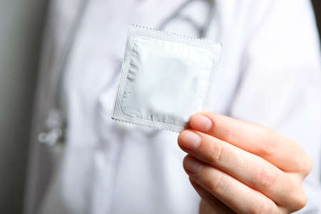 condoms in the hands of a doctor in a white coatの写真素材
