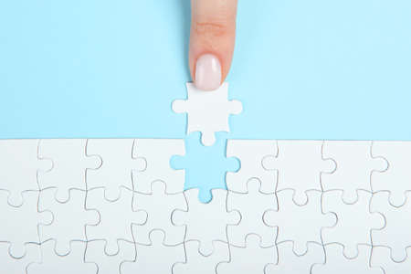 Collect puzzle. Hand and puzzle pieces on the table. High quality photoの写真素材