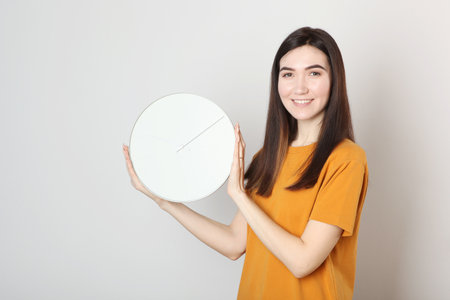 Girl holds a mechanical clock on a colored backgroundの写真素材