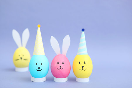 Easter eggs with cute faces and ears on a colored background.