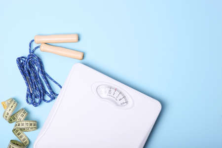 floor scales, tape measure and healthy products on a colored background top view