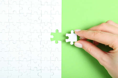Collect puzzle. Hand and puzzle pieces on the tableの写真素材