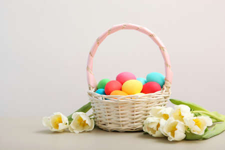 Easter eggs in a basket and flowers on the table.の写真素材