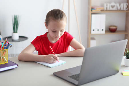 A child learns online at home through a modern laptop on the Internet.の写真素材