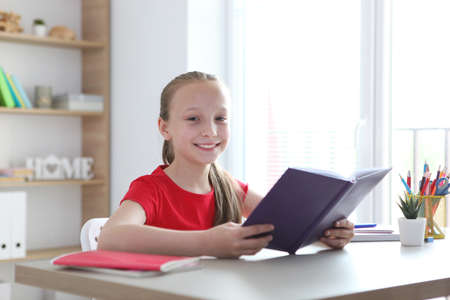 little girl reads a book at home.