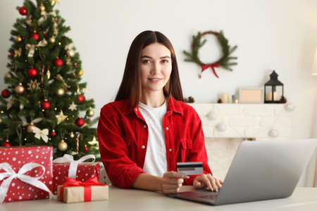Young beautiful woman is shopping for christmas in festive interior at homeの写真素材