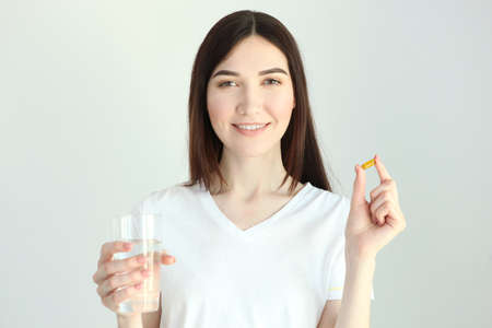 Young woman takes fish oil capsules at homeの写真素材