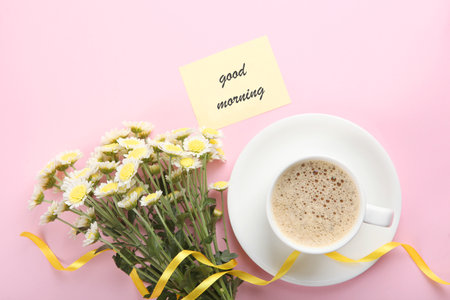 A cup of coffee, a bouquet of flowers and a card with the words good morning.の写真素材
