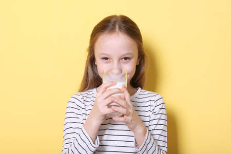 Child with glass of milk on a colored background.の写真素材