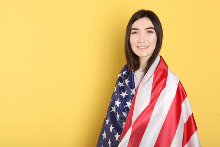 Beautiful young girl holding the flag of America on a colored background.の写真素材