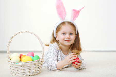 Cute little girl with easter basket on a light background.