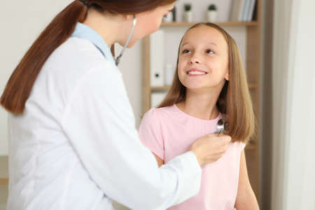Young girl doctor pediatrician makes a checkup to a little girlの写真素材