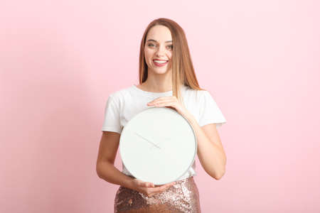 Girl holds a mechanical clock on a colored backgroundの写真素材