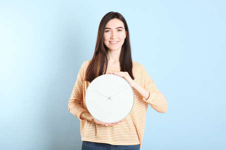 Girl holds a mechanical clock on a colored backgroundの写真素材
