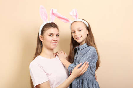 Mom and daughter with rabbit ears on a colored background.の写真素材