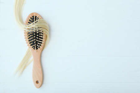 A lock of blonde hair, hair care products and a comb on a colored backgroundの写真素材