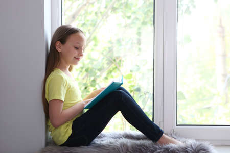 little girl reads a book at home.の写真素材