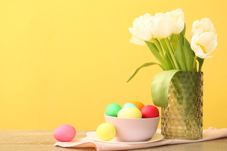Easter eggs in a basket and flowers on the table.