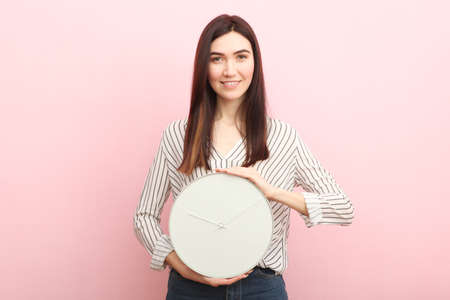 Girl holds a mechanical clock on a colored backgroundの写真素材