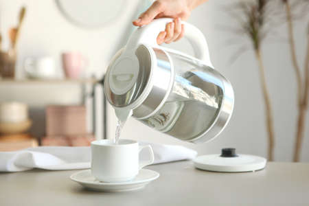 Pure water boils in an electric kettle on the table in the kitchen