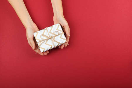 gift in female hands on a colored background top view.の写真素材