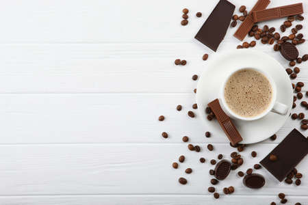 cup of coffee, coffee beans and chocolate on the table close up