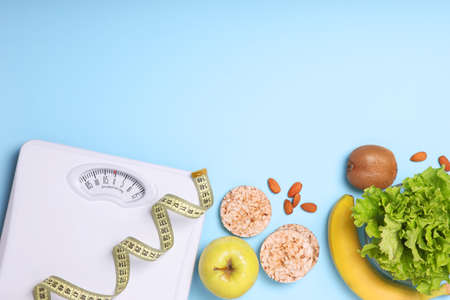 floor scales, tape measure and healthy products on a colored background top view