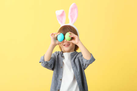 Little cute boy with Easter eggs in his hands and bunny ears on his head