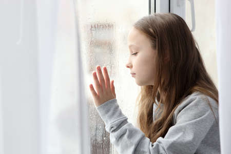 Lonely sad girl at home. saddened alarmed child alone at home.の写真素材